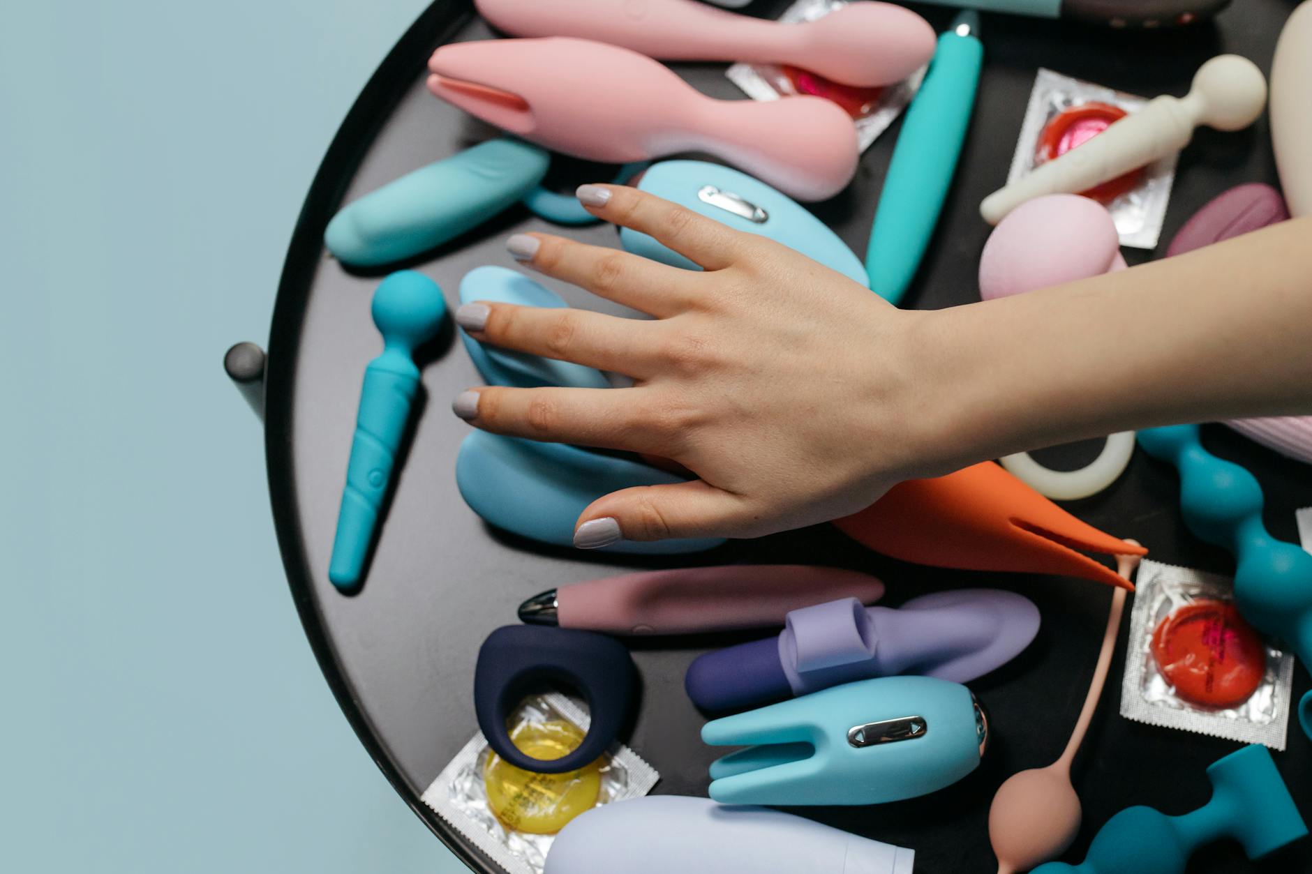 Woman holding blue and pink clitoral vibrators thoughtfully
