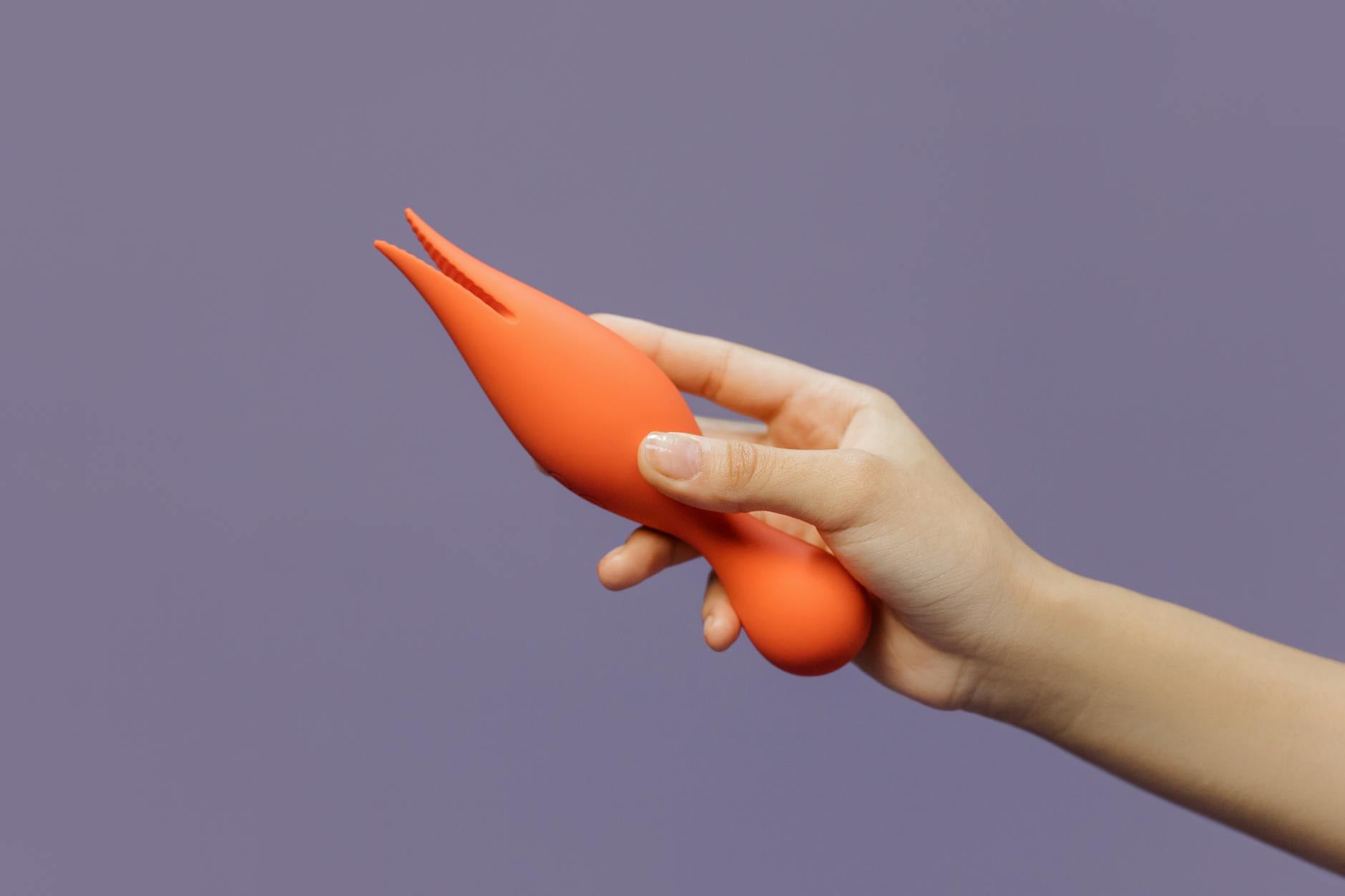 A young couple standing together indoors, holding a blue vibrator, symbolizing modern intimacy and shared pleasure.