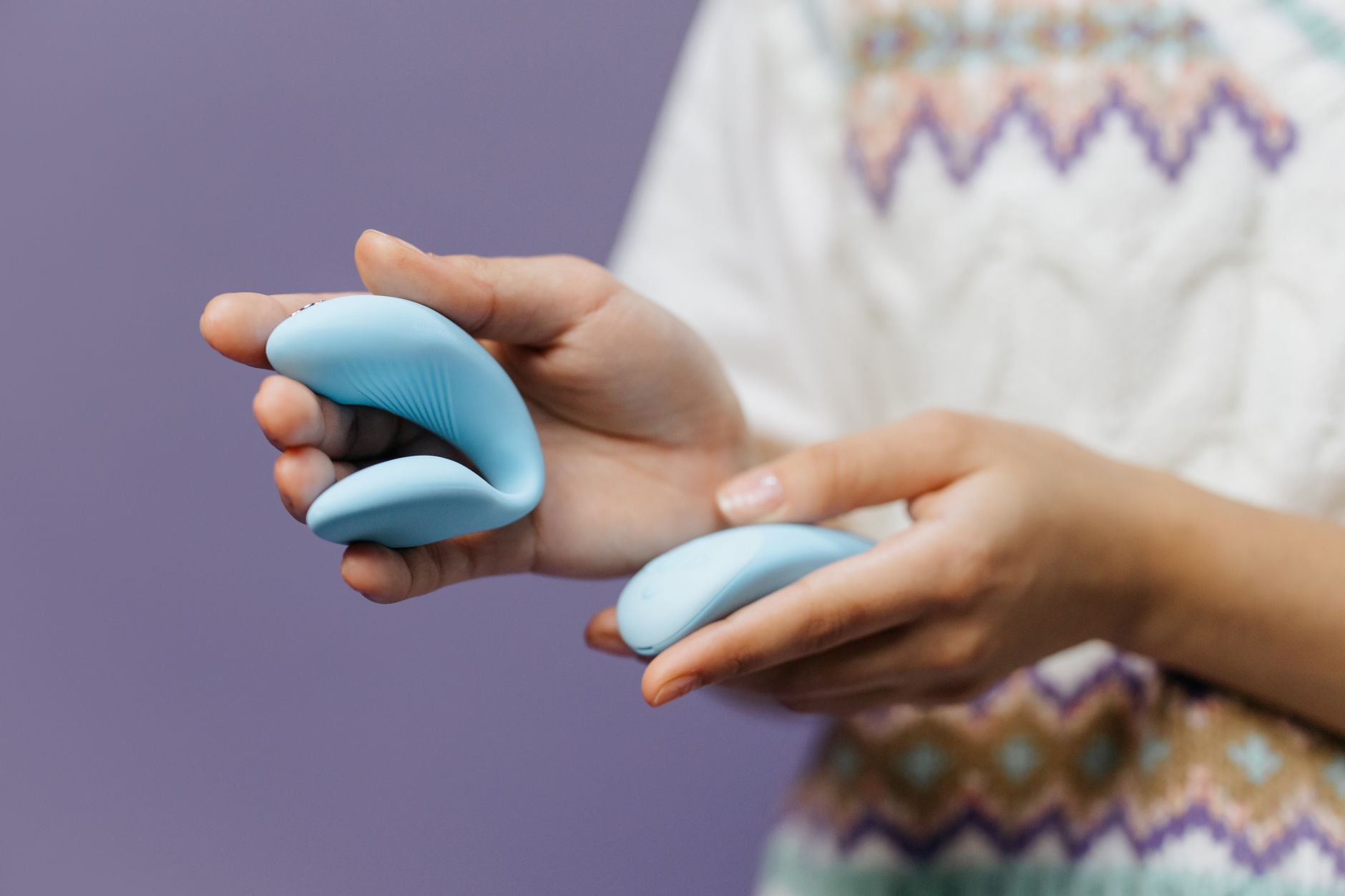 Woman holding a sleek clitoral vibrator against a purple background, emphasizing personal control and pleasure.