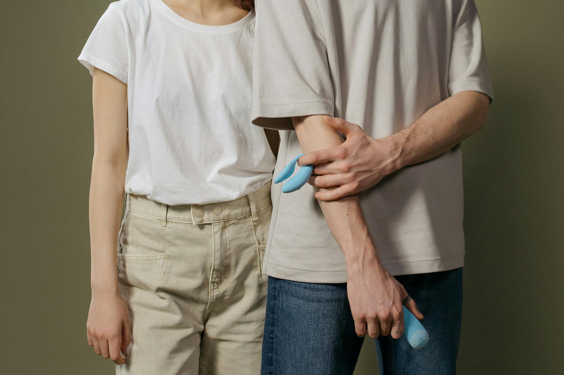 Hand holding a blue silicone vibrator against a purple background, demonstrating proper grip and control.