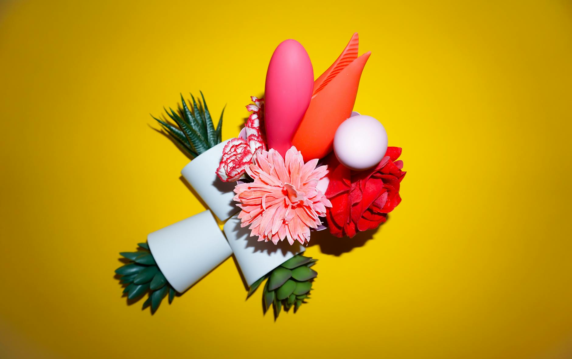 Colorful vibrators with flowers in a holistic gift bag, set against a bold yellow background