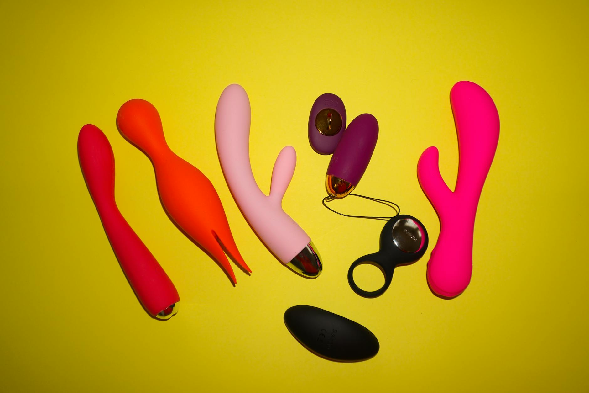 Colorful vibrators and adult toys arranged on a bright yellow background
