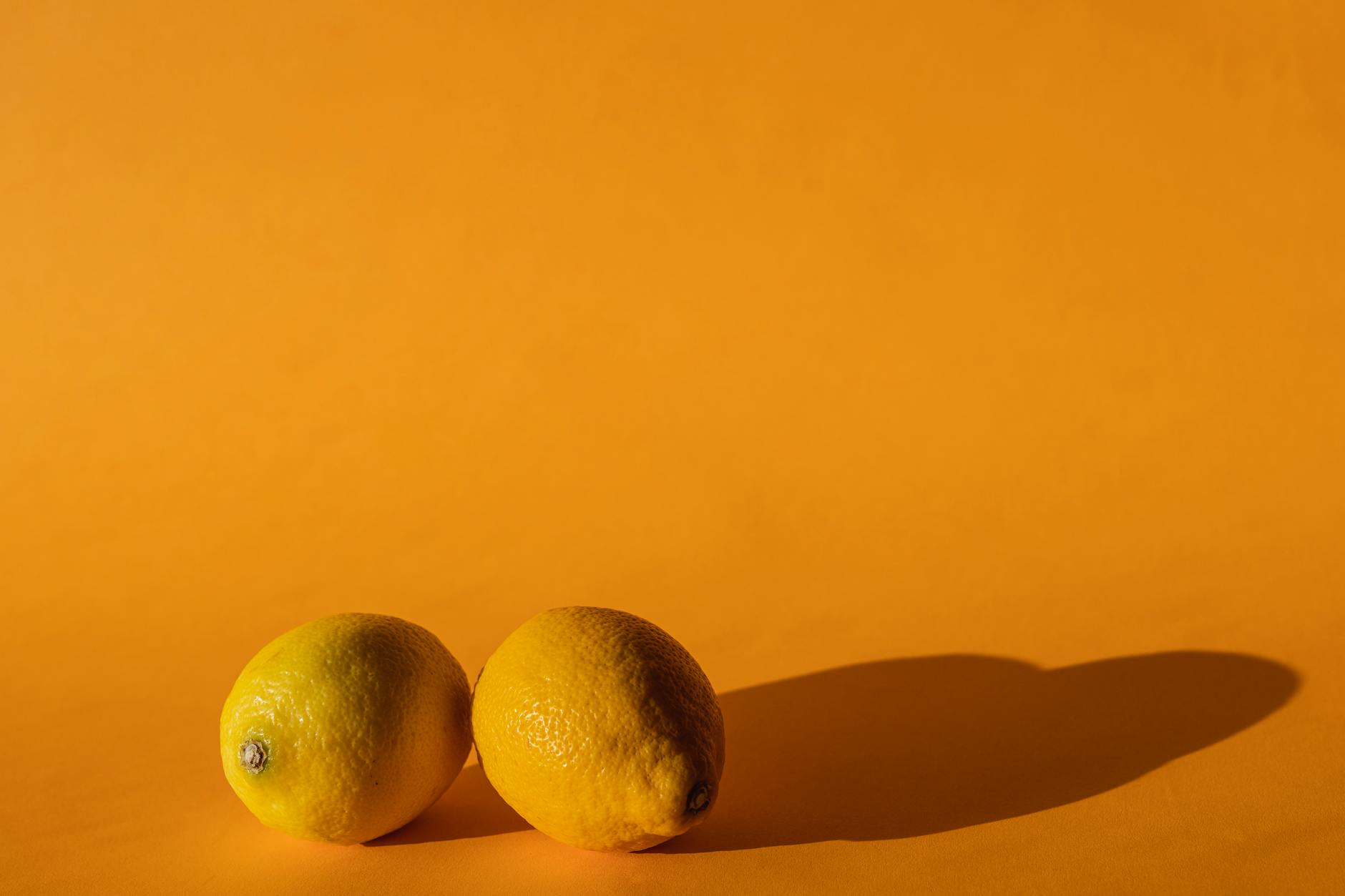 Bright ripe lemons on yellow background representing natural wellness and recovery